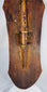 Historic cracks, surface wear, and old stabilization visible on the carved wooden shield