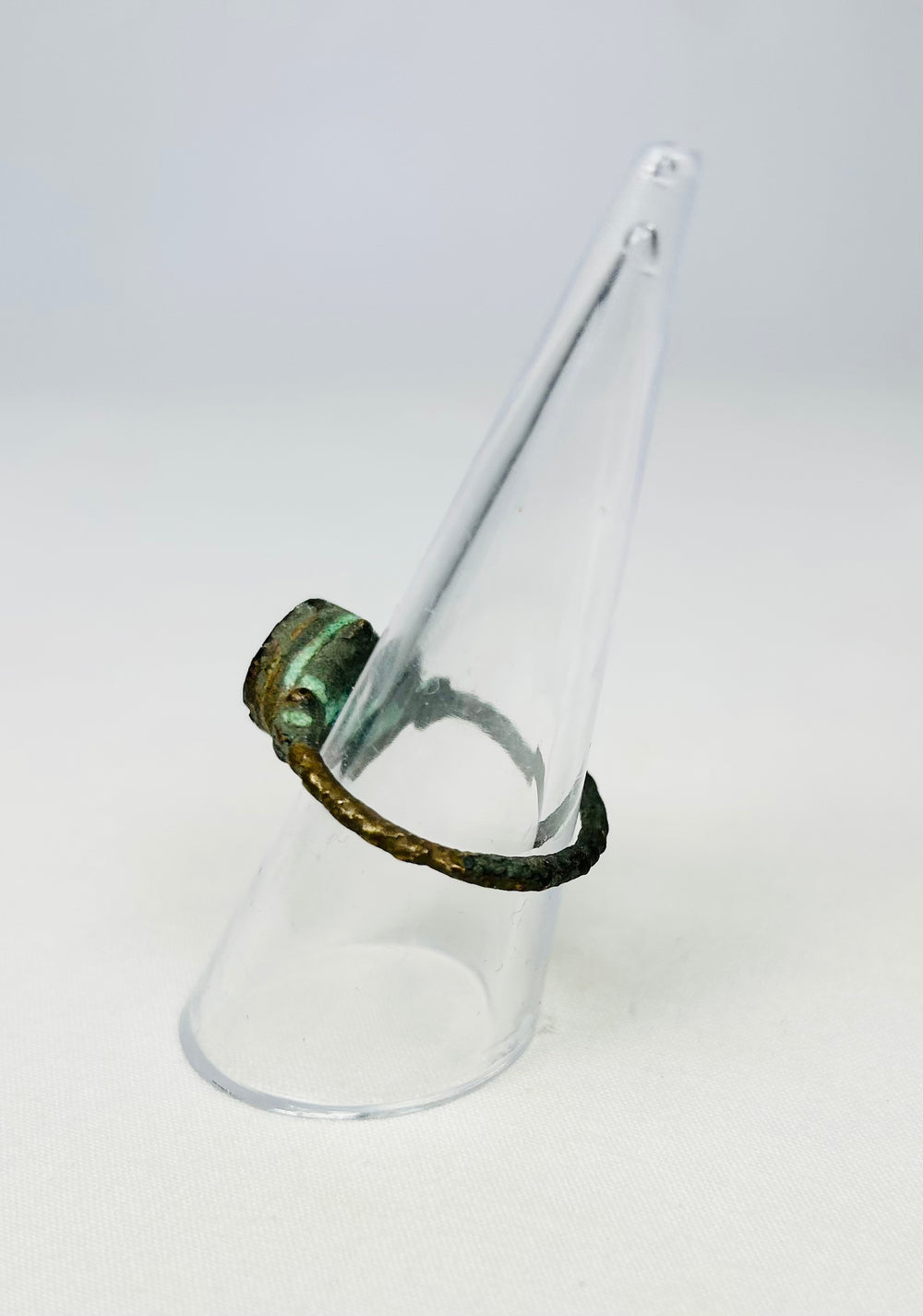 Side profile of a corroded bronze ring showcasing aged metal texture