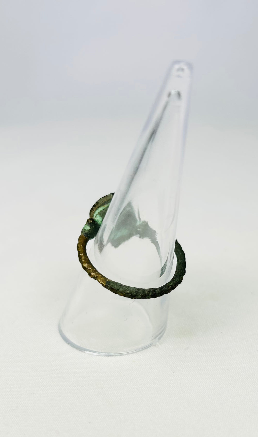 Antiquity-era bronze ring with circular bezel on a museum display cone