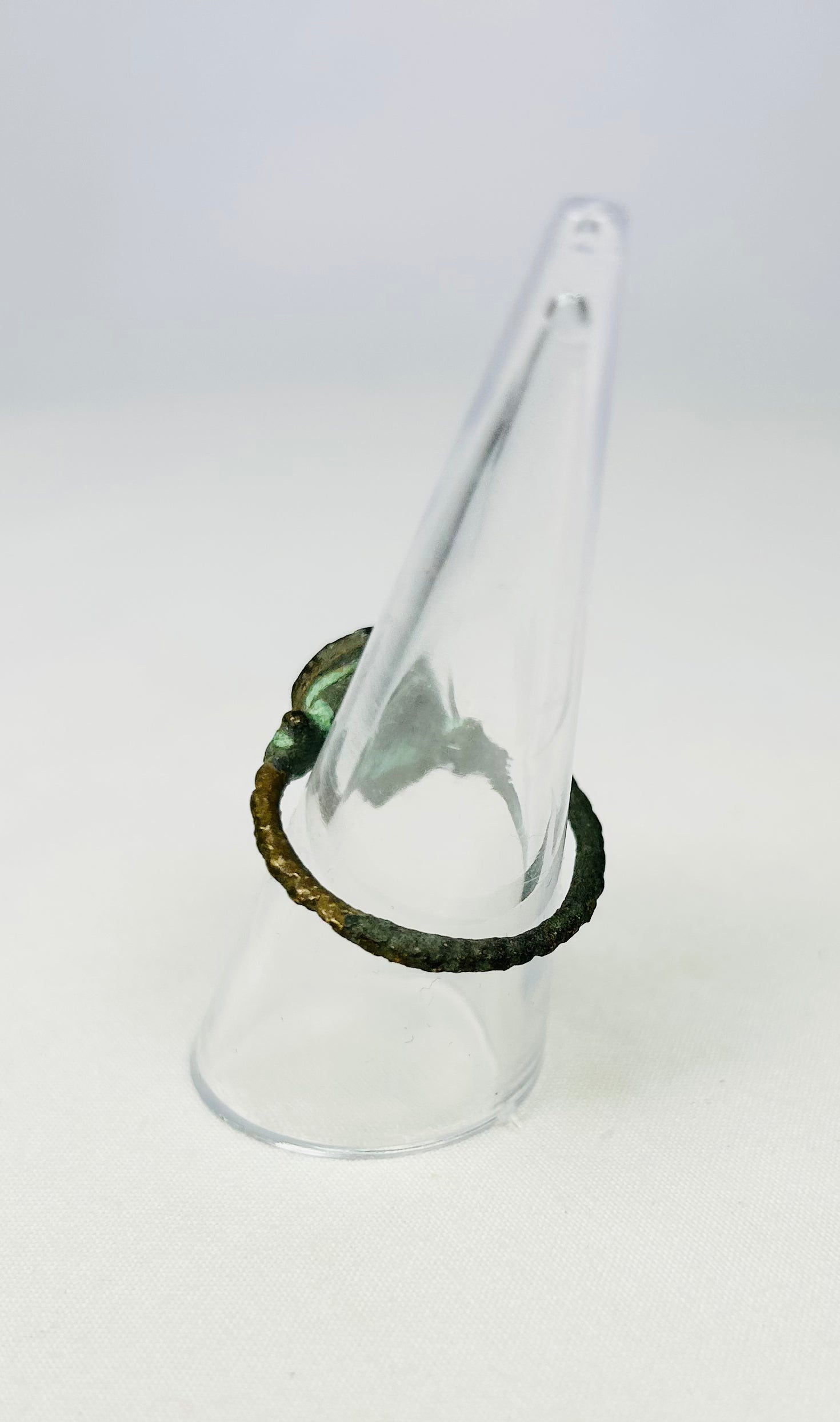 Antiquity-era bronze ring with circular bezel on a museum display cone