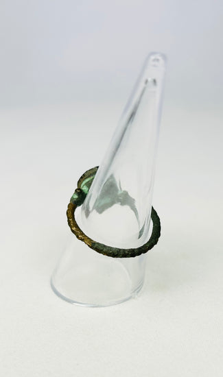 Antiquity-era bronze ring with circular bezel on a museum display cone