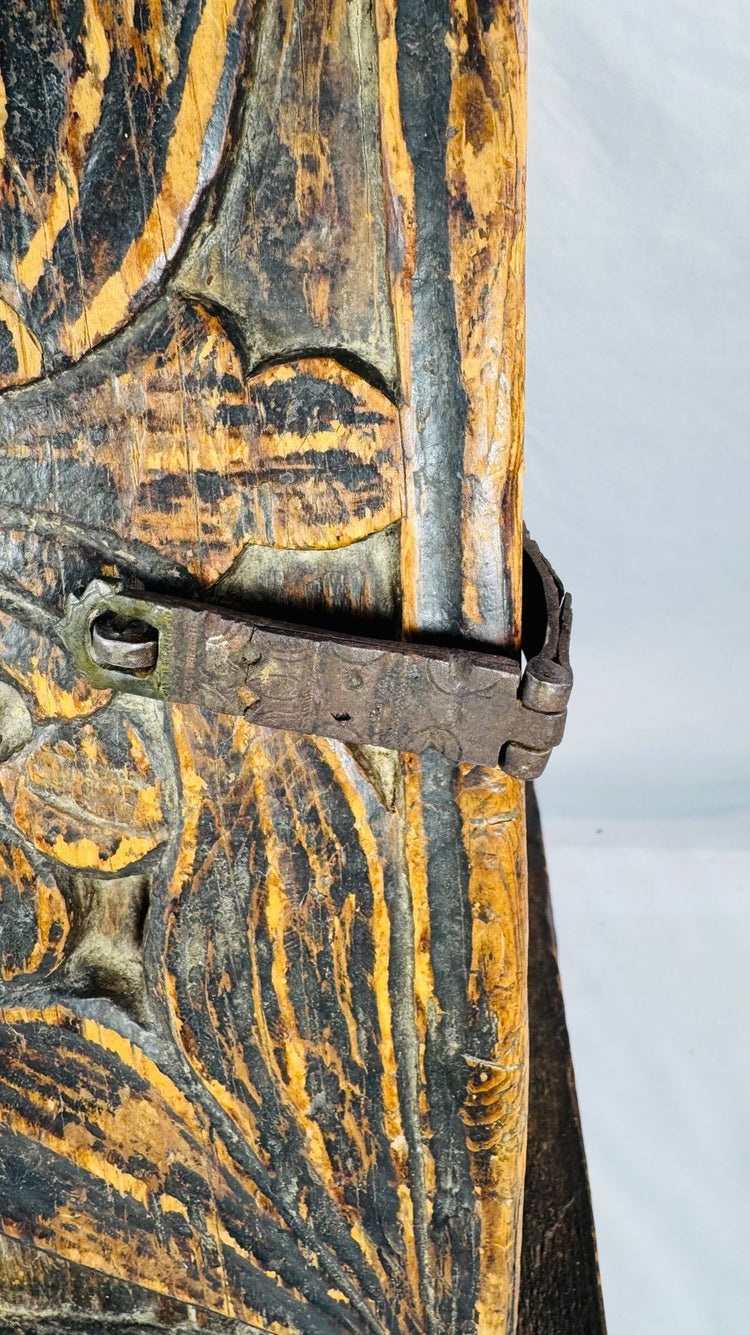 Oxidized iron strap latch mounted on a traditional carved wooden cabinet