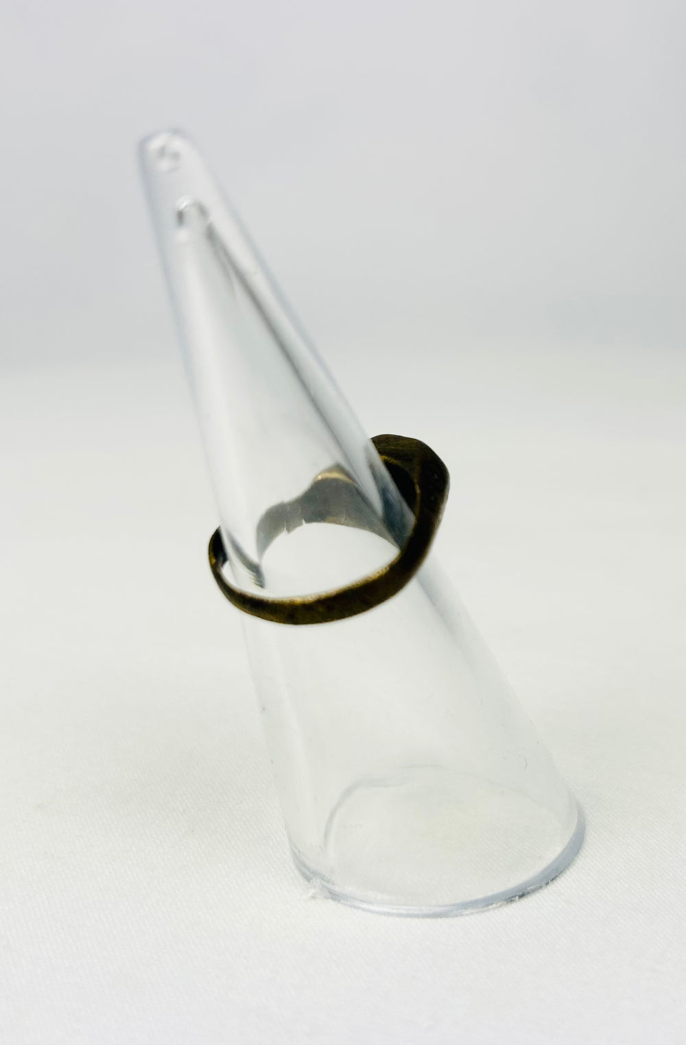 Ancient metal ring with incised geometric design on stand