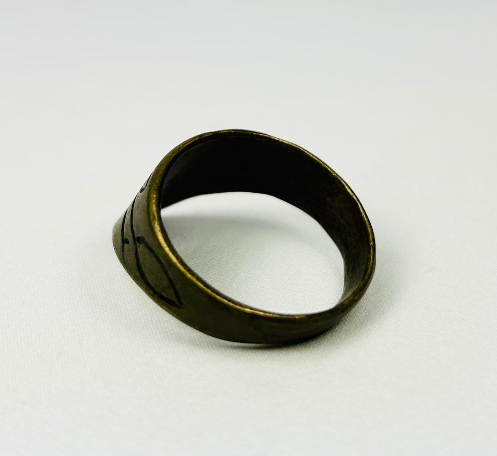 Close-up of engraved motifs on brass thumb ring