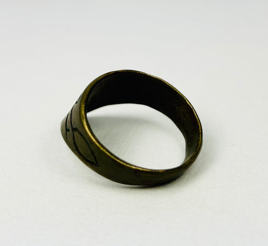 Close-up of engraved motifs on brass thumb ring