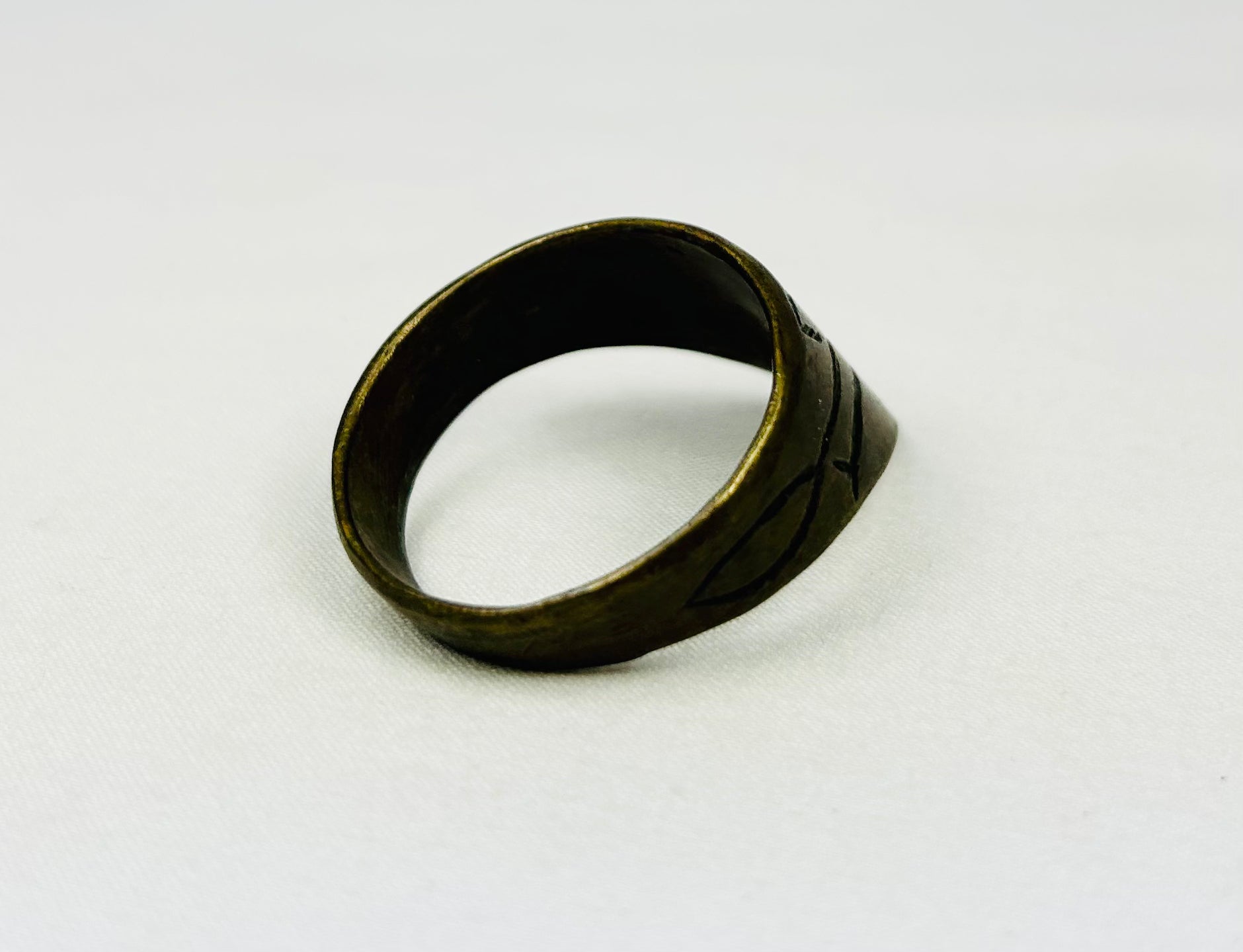 Angled view of antique thumb ring on white background
