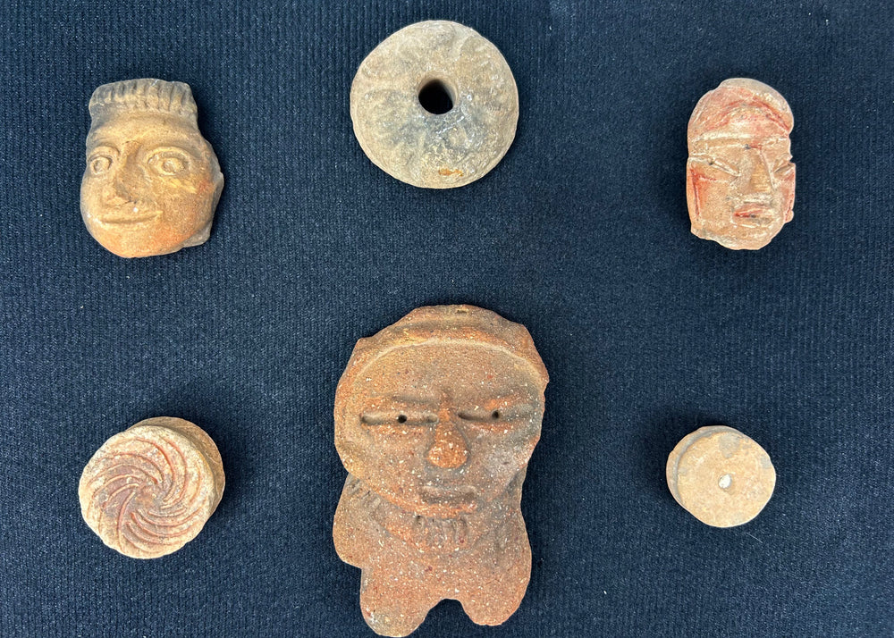 Museum-style presentation of ancient Mesoamerican artifacts in a black shadowbox