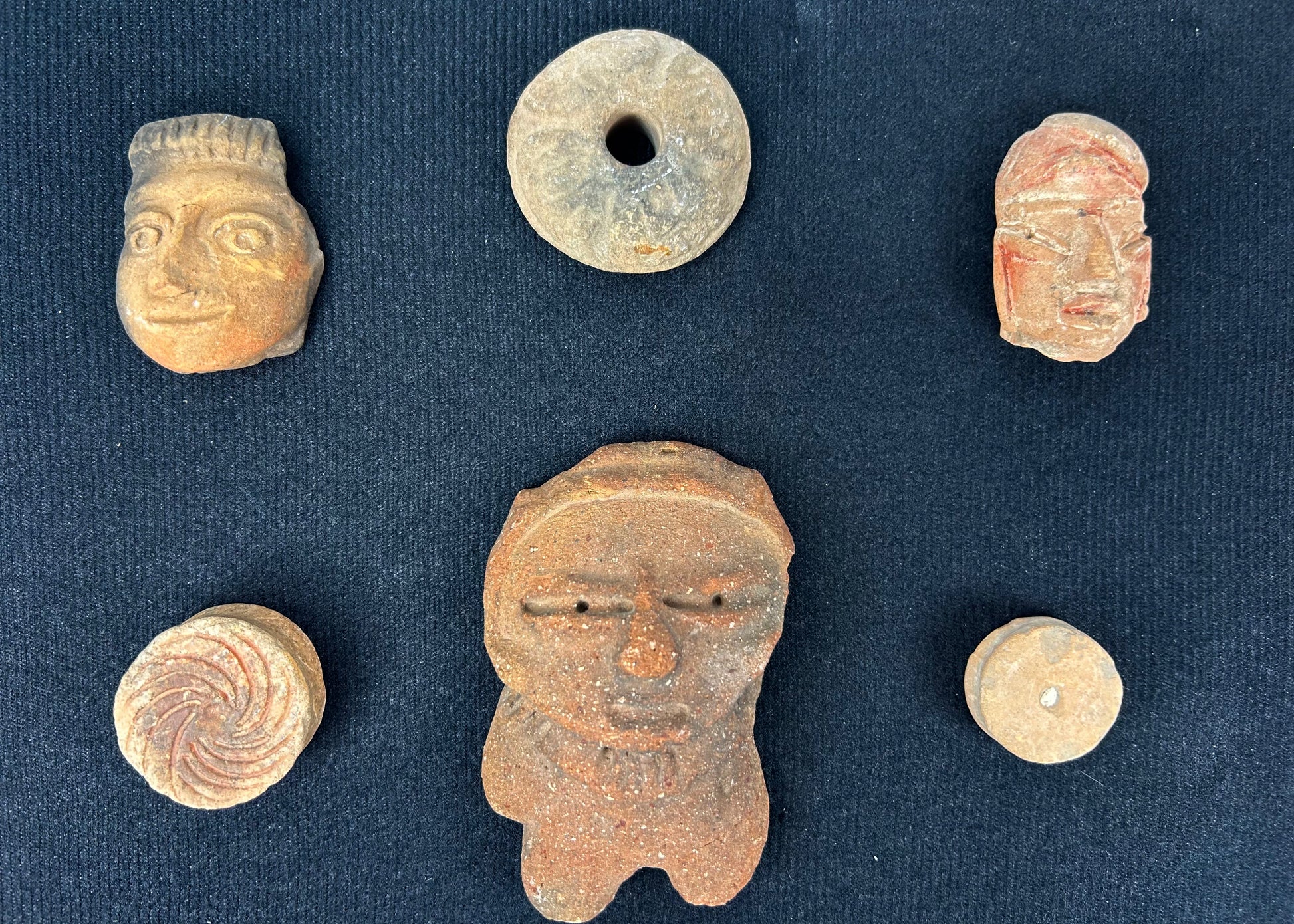 Museum-style presentation of ancient Mesoamerican artifacts in a black shadowbox