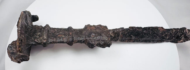 Close-up of the upper blade and hilt of a Luristan iron short sword, displaying corrosion and patina consistent with significant age.