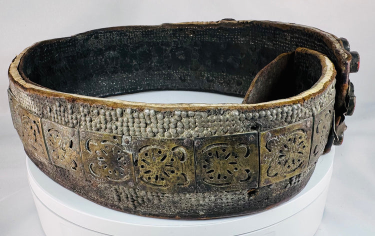 Side view of an antique Jewish ceremonial bridal belt showing its layered brass fittings, gemstone settings, and aged surface wear.