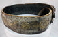 Side view of an antique Jewish ceremonial bridal belt showing its layered brass fittings, gemstone settings, and aged surface wear.