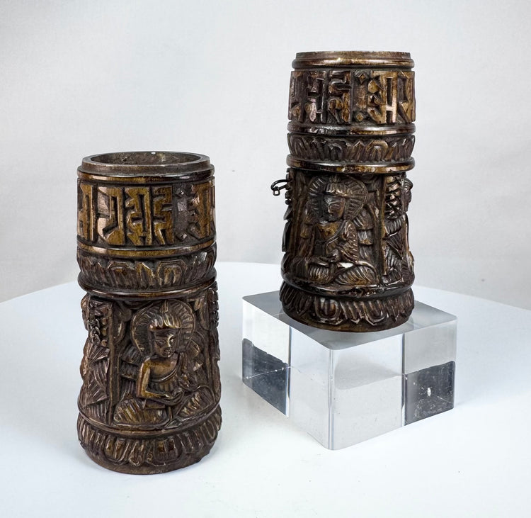 Tibetan ritual prayer wheels carved from human bone, featuring three relief-carved Buddha figures and bands of sacred inscriptions.