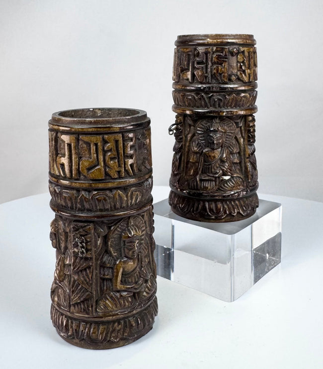 Close-up of hand-carved Buddha figures on Tibetan Buddhist human bone prayer wheels, each shown in a distinct mudra.