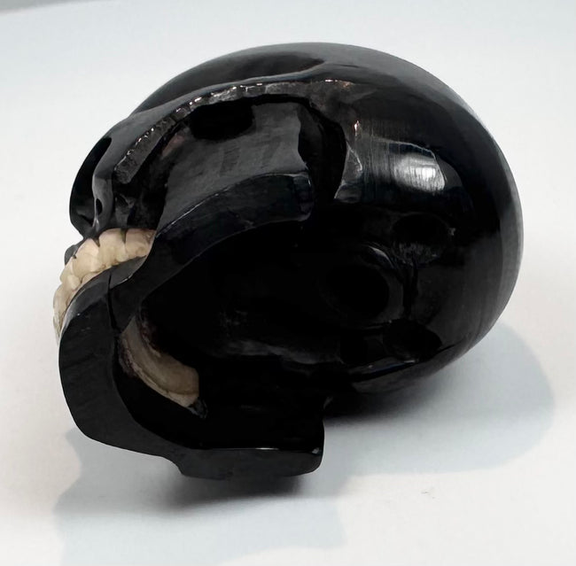 Small antique memento mori skull displayed on a clear acrylic block
