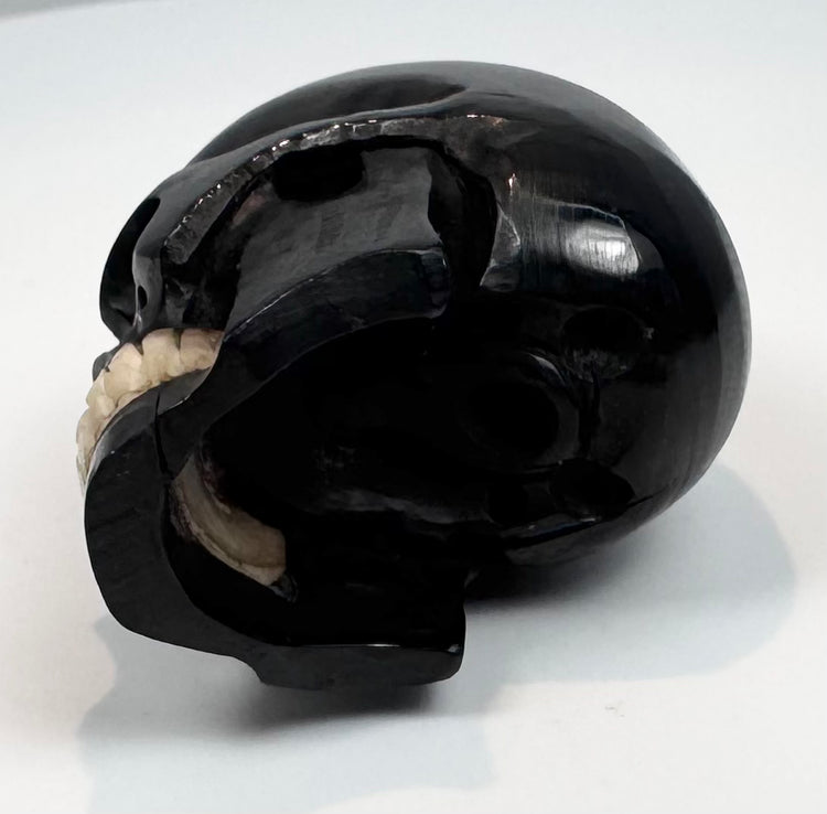 Small antique memento mori skull displayed on a clear acrylic block