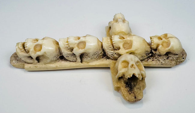Close-up of carved skulls and articulated teeth on an antique bone cross
