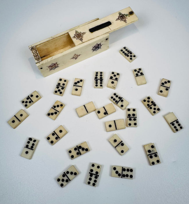 Open sliding-lid case containing miniature 19th-century bone dominoes