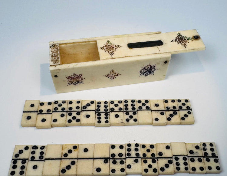 Miniature antique domino set arranged beside its decorated bone box