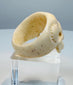 Close-up of carved teeth, nasal cavity, and recessed eyes on a bone skull ring