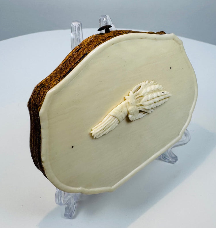Detailed hand-carved wheat and grain ornament on an antique bovine bone purse