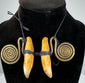Close-up of aged animal teeth secured with black woven cord and brass ornamentation