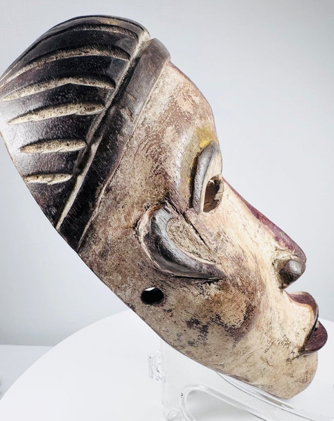 Expressive Yombe cultural mask with cream-colored face and dark contrasting details