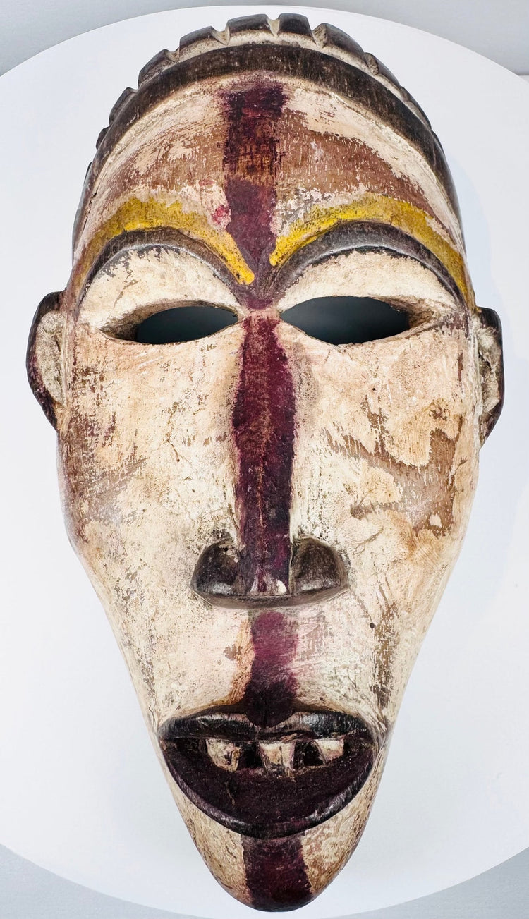 Front view of a carved Yombe mask with narrow eyes, prominent nose and open mouth