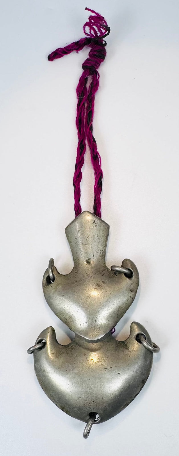 Antique Chinese double crescent amulet pendant suspended from an aged magenta textile cord