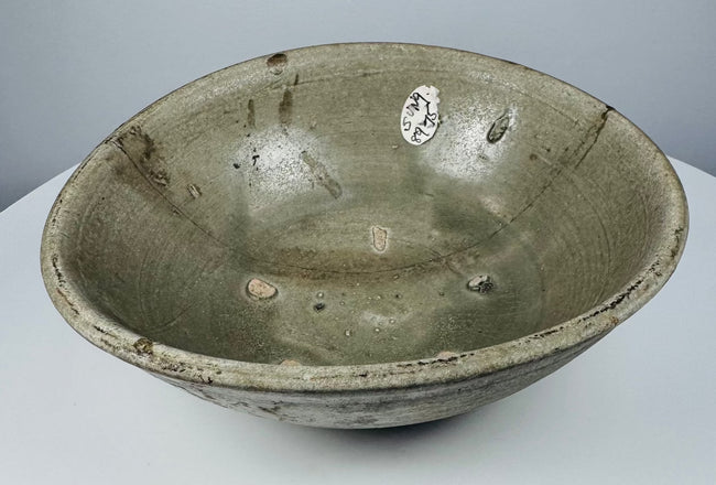 Full view of an early Southeast Asian celadon bowl with rounded sides and an everted rim