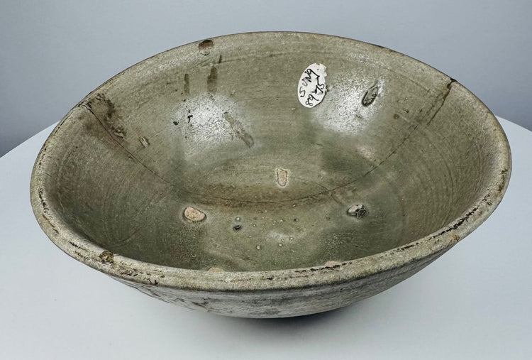 Full view of an early Southeast Asian celadon bowl with rounded sides and an everted rim