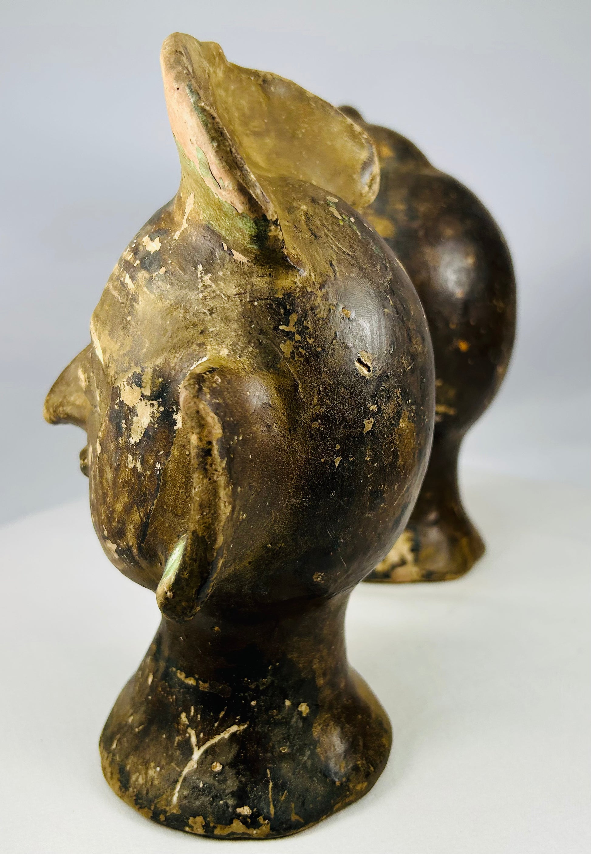 Hand-formed terracotta head sculptures with prominent ear ornaments and aged patina