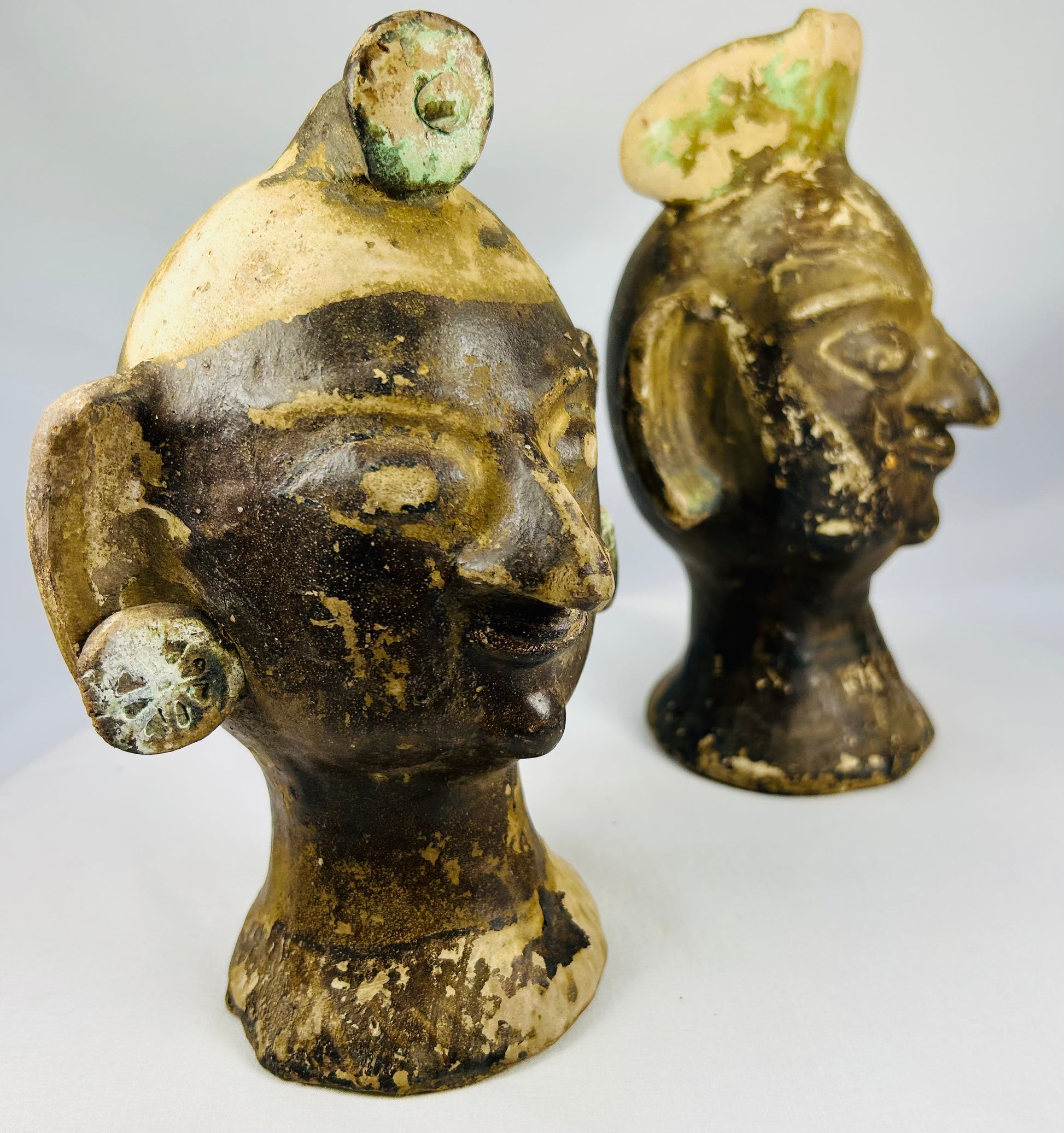 Dark brown slipped terracotta heads with mineral surface deposits and hollow construction