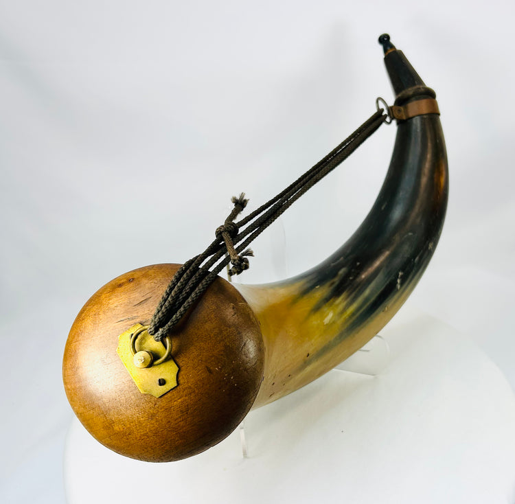 Historic flintlock period powder horn featuring wooden butt plug and brass suspension ring