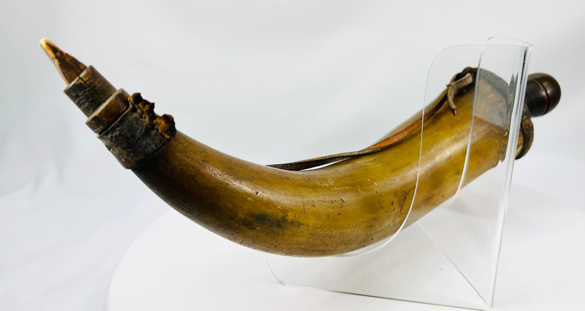 Antique frontier or militia powder horn with horn body, wood plug, and leather strap traces