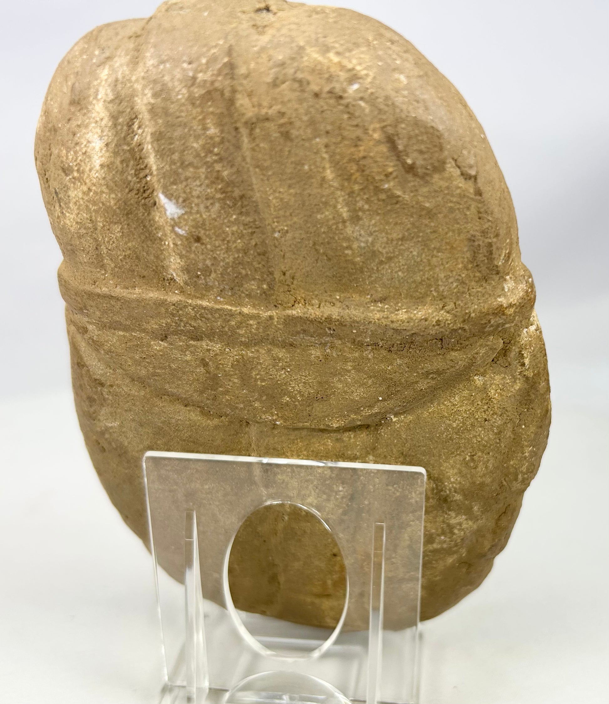 Hand-carved stone effigy plaque depicting helmeted warrior face