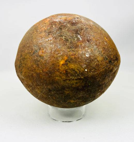 Museum-style display of historic iron cannonball with textured aged surface