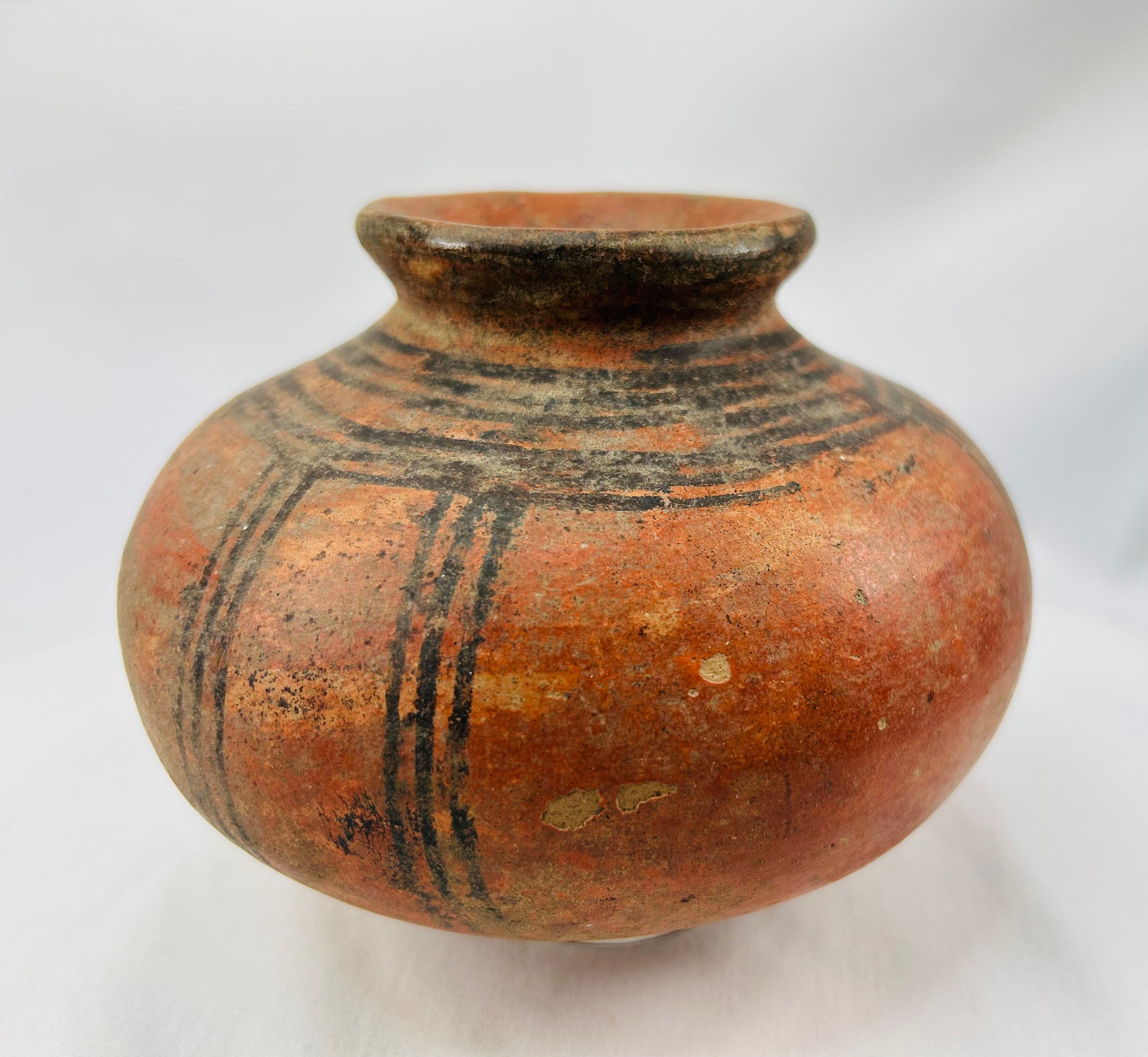 Traditional West African hand-coiled terracotta vessel with painted designs