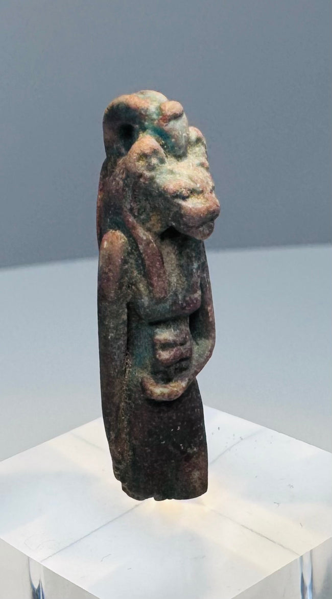 Close view of the lioness head, rounded ears and recessed eyes on an ancient faience amulet
