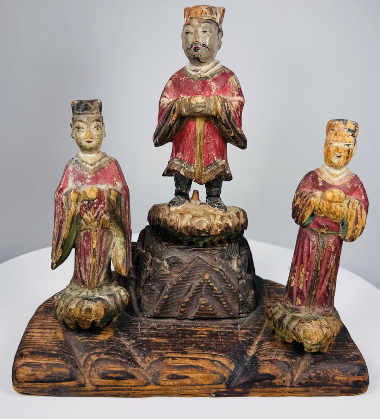Two flanking attendants in red robes standing upon individual carved lotus-form pedestals