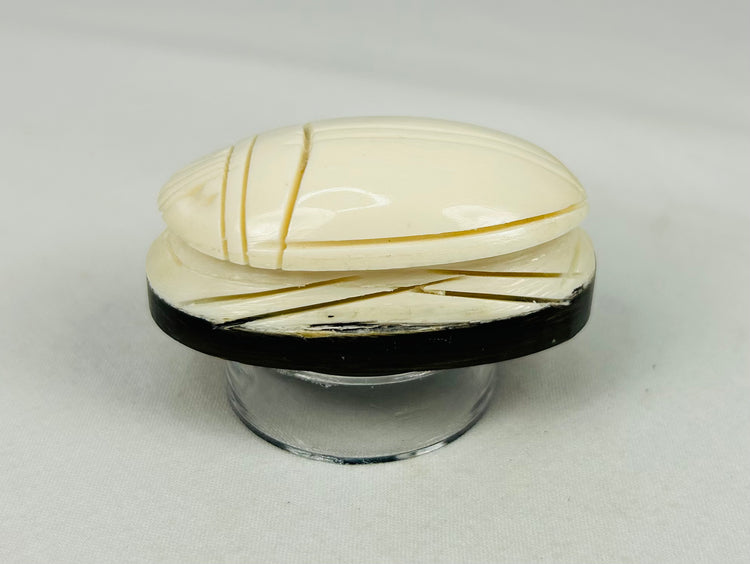 Close-up of ivory-style East Asian carved scarab showing detailed linear carving
