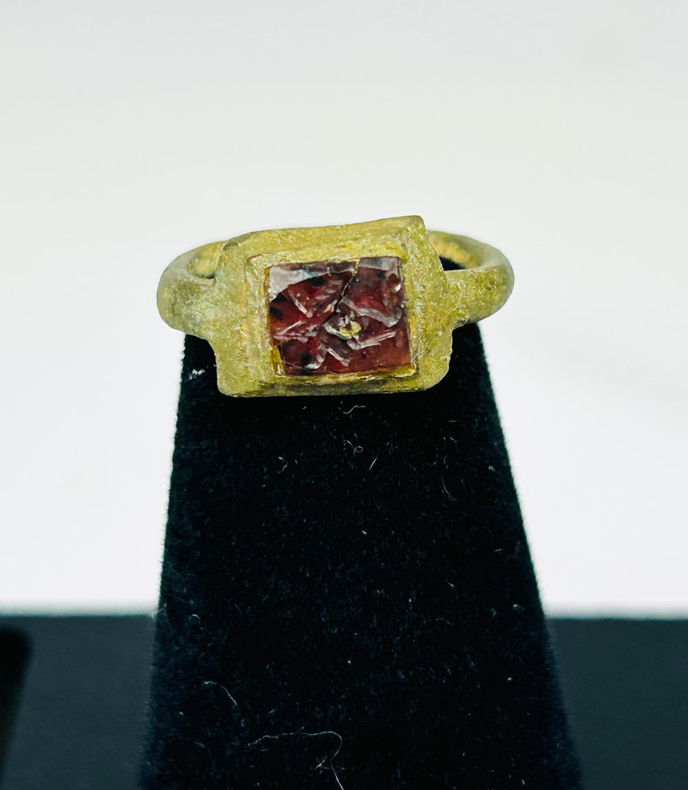 Close-up of 2nd-century Roman bronze ring showing square bezel and red glass stone
