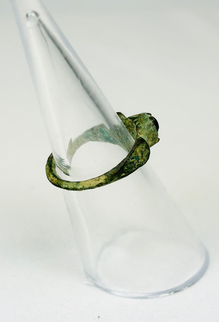 Three-quarter angled view of ancient Roman bronze ring with securely seated garnet gemstone