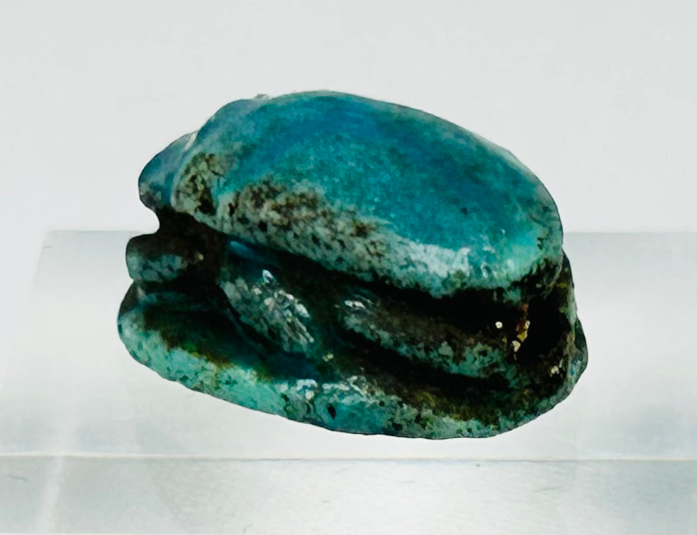 Three-quarter angled view of ancient Egyptian scarab with vivid blue-green glaze patina