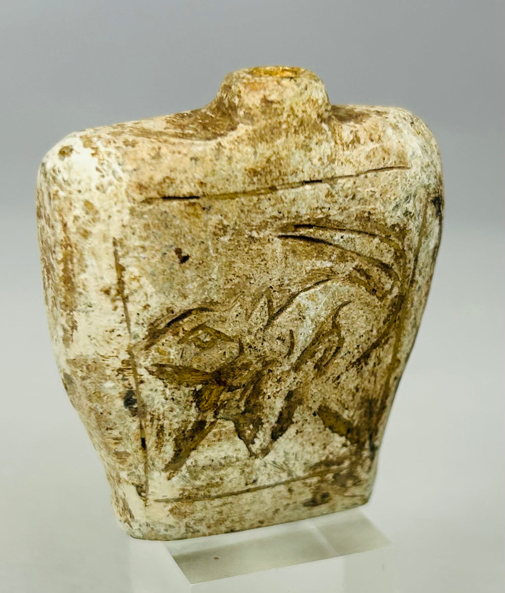 Close-up of carved ancient stone amulet flask showing detailed relief design