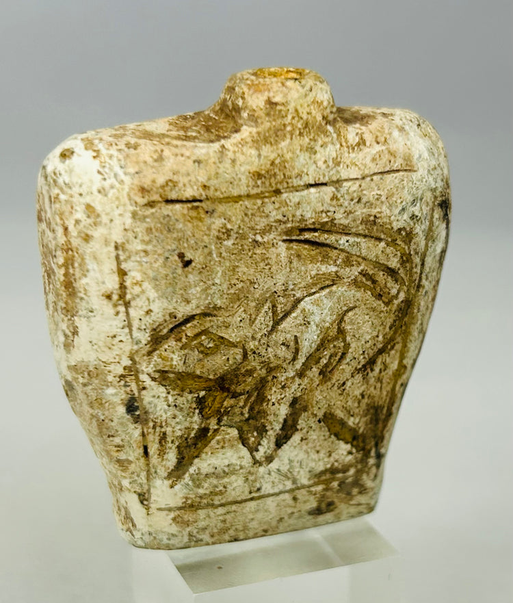Close-up of carved ancient stone amulet flask showing detailed relief design
