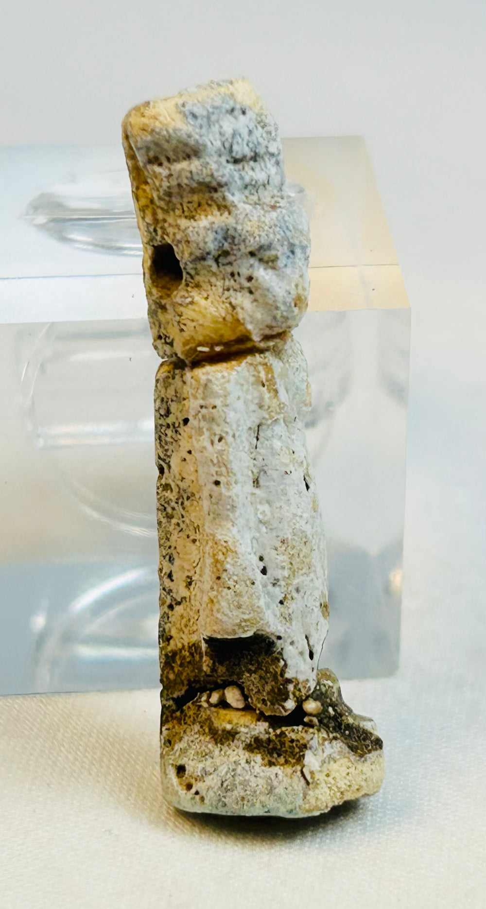 Close-up image of weathered Egyptian faience amulet displaying mineral accretion.