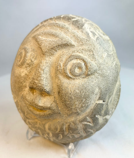 Side profile of carved stone face effigy showing engraved decorative details