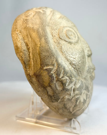 Hand-carved stone face with whimsical expression and folk art character