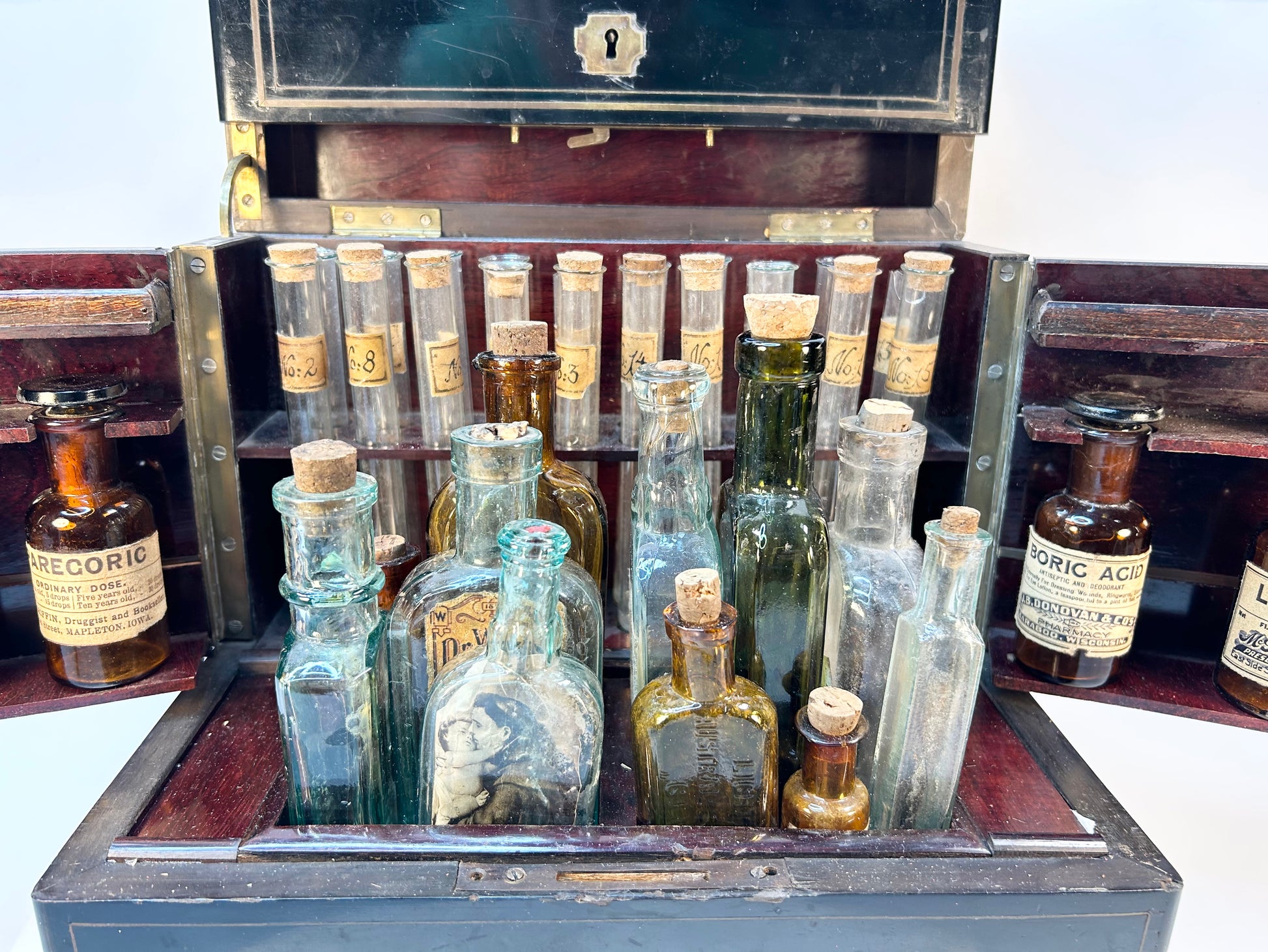 Row of antique glass pharmaceutical vials with handwritten Victorian labels