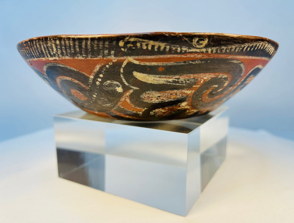 Antique hand-painted Pre-Columbian pottery bowl displayed on clear museum stand
